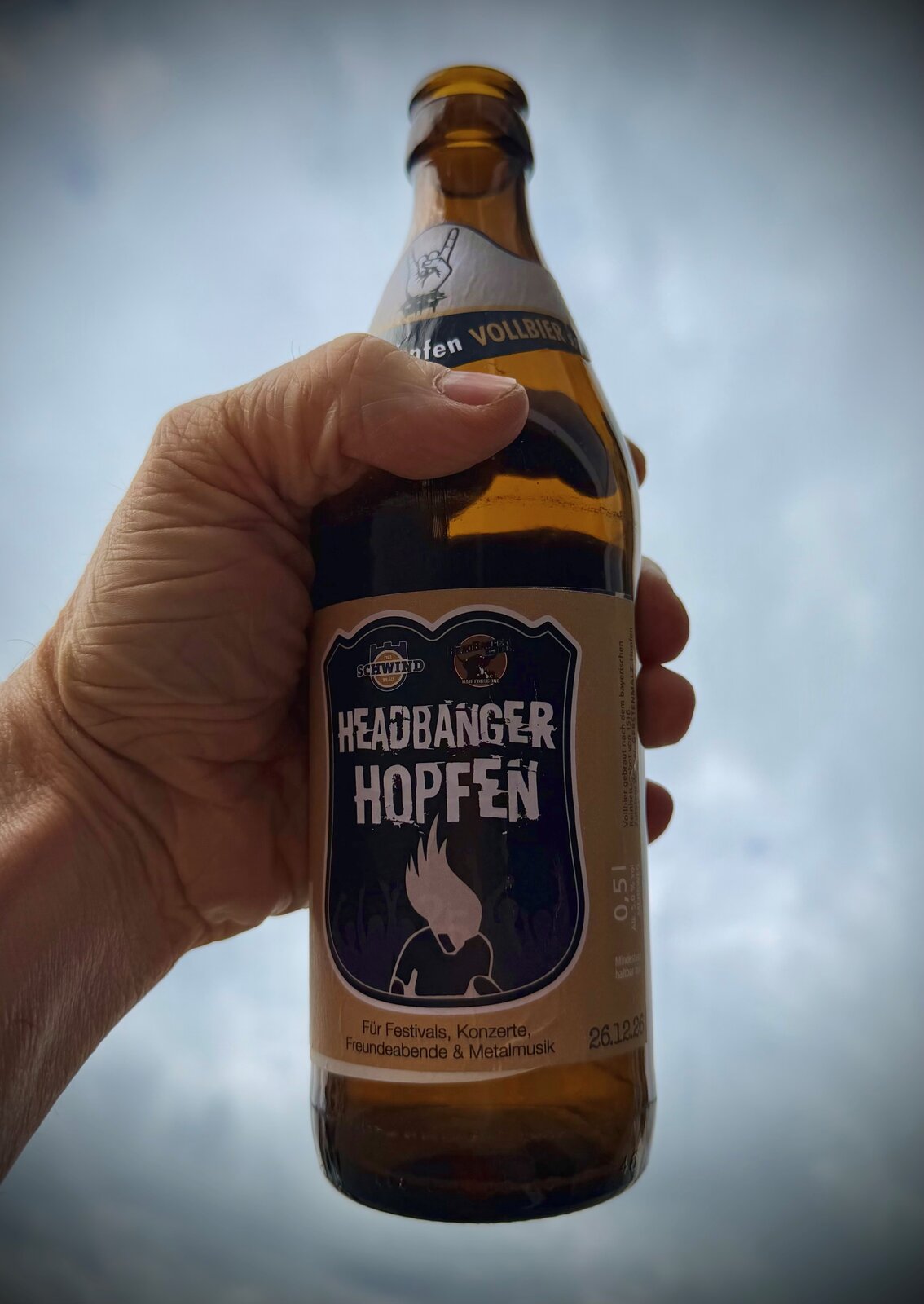 Headbanger Hopfen stolz in der Hand gegen den Himmel
